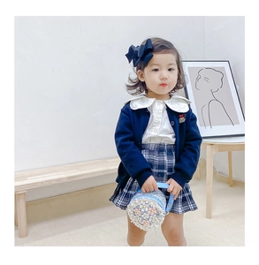Girl's outfit featuring blue knit cardigan, plaid skirt and floral chain round bag