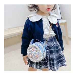 Detail of blue tweed girl bag with pearl decor and 3D flowers on a young model