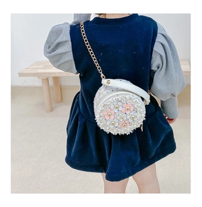 Close-up of girls floral round crossbody bag with pearls and sequins on a mini chain