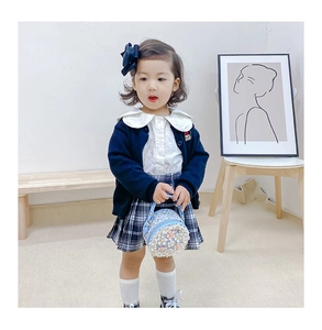 Close-up of light blue round bag with 3D flower detail paired with kids spring outfit