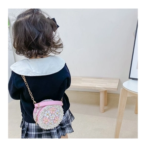 Detail showing a girl wearing the pink round chain bag with 3D floral petals and pearls