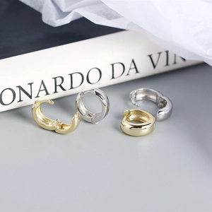 Detailed view of glossy gold and silver S925 sterling silver hoop earrings set on book
