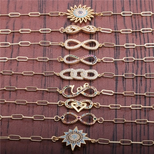 Gold-plated infinity and star cubic zirconia charm bracelets on wooden background