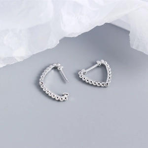 Macro detail of S925 sterling silver heart earrings crafted with tiny metallic beads