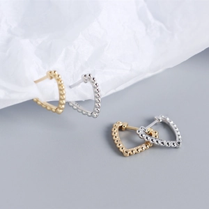 Detail view of gold and silver heart earrings with visible 925 sterling silver hallmark
