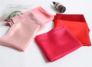 Flat lay of folded silk scarves in various shades of pink and red on a white base