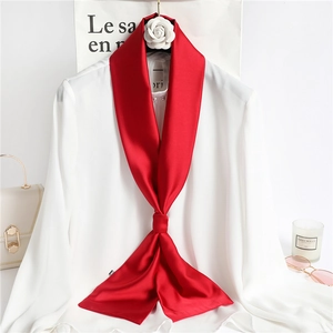 Detail of red satin skinny scarf styled on white shirt with elegant fashion accessories