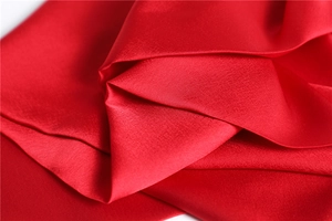 Macro shot of smooth red satin fabric showing glossy texture and soft drape detail
