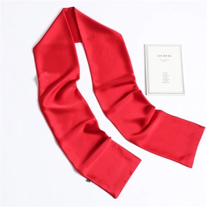Close-up of red silk satin scarf with elegant drape and minimalist fabric label