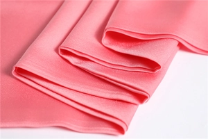 Close-up of pink satin silk fabric showing smooth texture and soft natural folds