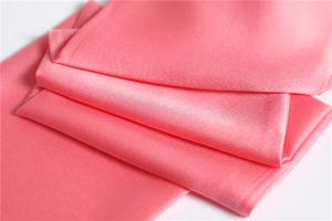 Close-up of soft pink satin silk scarf fabric showing smooth texture and elegant folds