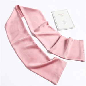 Flat lay of soft pink narrow silk scarf with smooth glossy texture next to a book