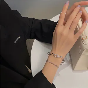 Dettaglio di bracciali a catena d'argento a strati con strass e anello aperto con perla
