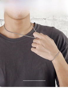 Close-up of minimalist silver woven chain necklace and bracelet set on male model