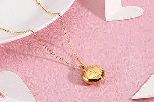 Detail of gold Virgo zodiac pendant with sparkling zircon on a romantic pink background