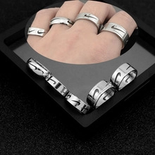Detailed macro view of silver stainless steel rings with engraved swoosh logos on a black box