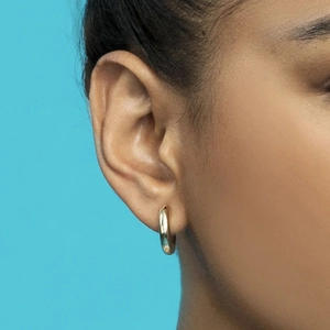 Elegant gold hoop earrings with polished geometric design shown on model's ear