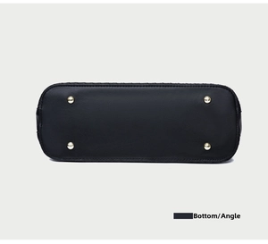 Detail view of the black textured leather handbag bottom with four protective gold metal studs