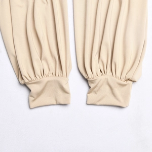 Detail view of beige jogger pants featuring elastic cuffs and smooth fabric texture
