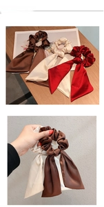 Close-up of three satin bow hair ties in brown, beige, and burgundy with long ribbons
