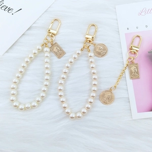 Detailed close-up of golden portrait medallions and pearl chain keychains on white fur