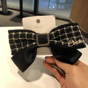 Détail d'une pince à cheveux nœud en tweed noir avec lettrage Smile doré élégant