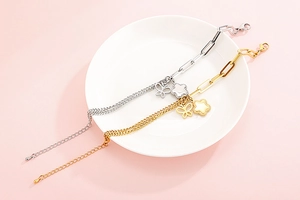 Dettaglio di bracciali a farfalla e fiori in oro e argento con catene a maglie miste