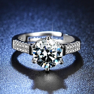 Macro shot of silver six-prong moissanite ring with pave diamonds on blue texture