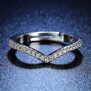 Macro shot of V-shaped silver ring with sparkling zircon stones on a dark background