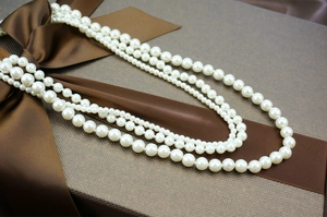Detail of multi-layer white faux pearl necklace elegantly placed on a brown gift box