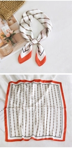 Detail view of square silk scarf with gold chain pattern and orange borders on white