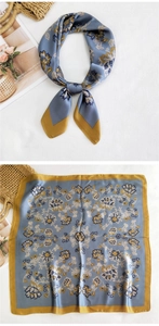 Close-up of a blue and yellow floral silk scarf tied elegantly on a white linen surface