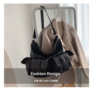Detail view of a black leather tote bag with functional buckle pockets and sleek crescent shape