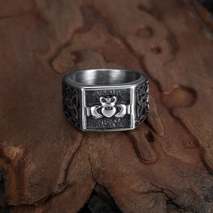 Vintage silver Claddagh ring with Celtic knot patterns on a dark wood background