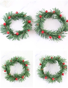 Detail of mini Christmas candle rings with green pine needles and red berries in a set of four
