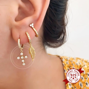 Detailed view of 925 sterling silver gold cross and feather earrings on model