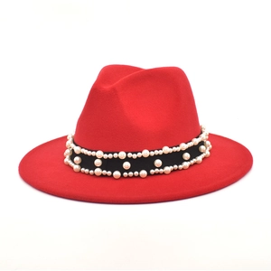 Detailed view of red wide brim fedora hat featuring black band with elegant white pearls