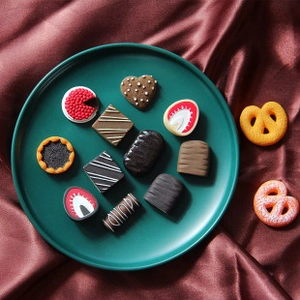 Miniature resin chocolate and dessert models displayed on a dark green decorative plate