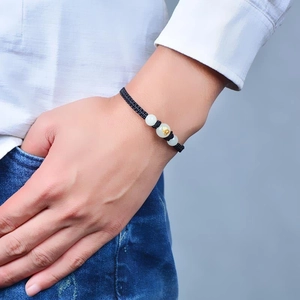 Handmade black braided cord zodiac bracelet with luminous beads worn on a male wrist