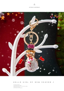 Detail of Christmas snowman keychain with white crystals and gold plating on festive tree