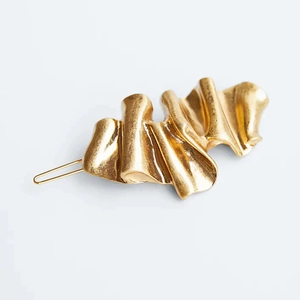 Macro shot of gold matte wavy hair clip showing textured metal folds and clamp detail