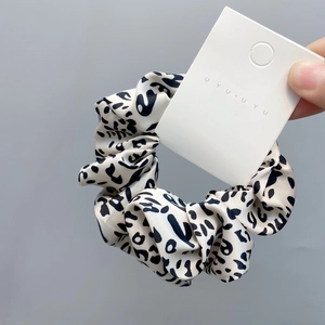 Detail of leopard print satin scrunchie with beige and black silk texture and tag