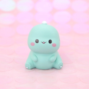 Cute green dinosaur cake topper figurine with pink bokeh background for birthday gifts