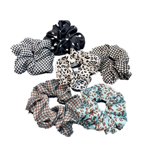 Close-up of assorted satin scrunchies with houndstooth, leopard print, and polka dot patterns