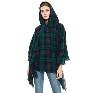 Dettaglio del poncho con cappuccio a quadri verde scuro con orlo a frange morbide