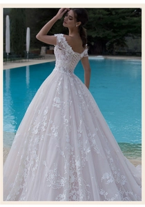 Detailed view of white lace wedding dress with intricate floral embroidery and corset tie back
