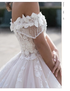 Detail of bridal dress featuring 3D floral lace and elegant beaded fringe sleeves