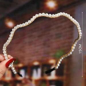 Detail shot of white faux pearl headband with 15cm size marker on gold metal frame