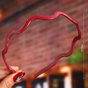 Detail view of wavy red plastic headband showing 13.7CM diameter size measurement