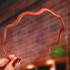 Detail of coral red wavy headband with non-slip teeth showing 13.7cm height dimension